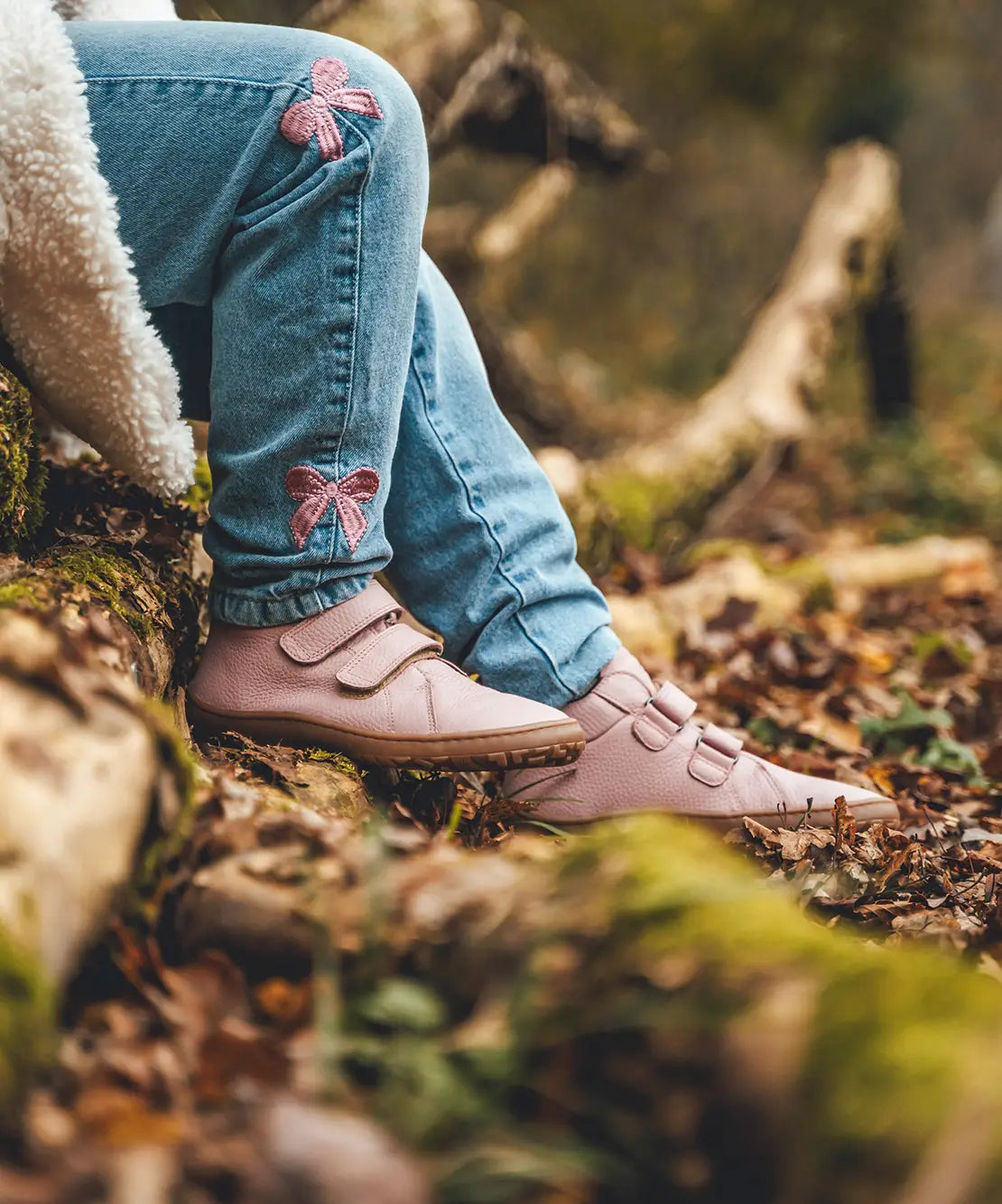 Child wearing Froddo natural leather kids barefoot shoe in pink in the forest. Hi-top boot has a flexible brown rubber sole and wide toe box