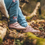 Child wearing Froddo natural leather kids barefoot shoe in pink in the forest. Hi-top boot has a flexible brown rubber sole and wide toe box