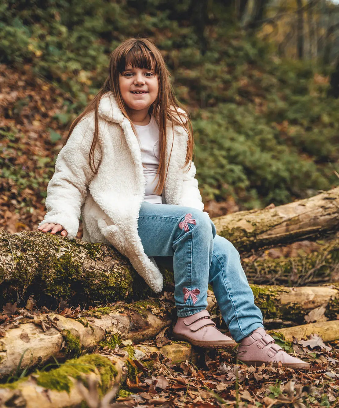 Child wearing Froddo natural leather kids barefoot shoe in pink in the forest. Hi-top boot has a flexible brown rubber sole, zero drop profile and wide toe box