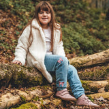 Child wearing Froddo natural leather kids barefoot shoe in pink in the forest. Hi-top boot has a flexible brown rubber sole, zero drop profile and wide toe box