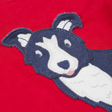 A close up of the Frugi kids adventure applique top berry red/sheepdog top showing the sheepdog applique detail on red organic cotton fabric.