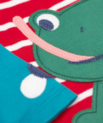A close up of the Frugi kids alfie raglan berry red breton frog top showing the playful green frog applique detial on organic cotton fabric.