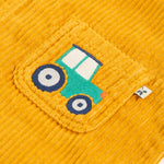 A closer look at the embroidered tractor on the pocket of the Frugi Adley Cord Dungarees - Gold/Tractor