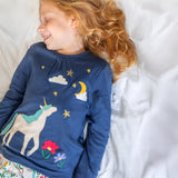 A child wearing the Frugi Organic Cotton Alana navy unicorn forest print children's Pyjamas available at Babipur. 