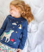 A child wearing the Frugi Organic Cotton Alana navy unicorn forest print children's Pyjamas available at Babipur. 