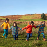 Children in a field and wearing Frugi's reversible, playtime, 3 in 1 rambler and tartan parka coats.