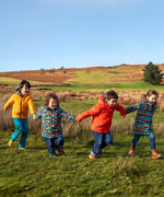 Children in a field and wearing Frugi's reversible, playtime, 3 in 1 rambler and tartan parka coats.