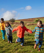 Children playing in a field and wearing Frugi's reversible, playtime, 3 in 1 rambler and tartan parka coats.