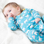 A baby lying on a white blanket, wearing the Frugi Easy Dressing Babygrow - Winter Tails