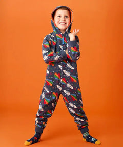 Frugi big organic cotton snuggle suit in blue with rainbow rocket and planet design, worn by child with hood up.