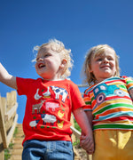Child wearing Frugi's happy tractor bobster applique t-shirt outdoors next to a child wearing a red tshirt with farm animals