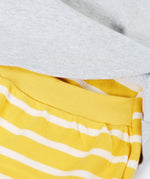 Frugi's baby all in one outfit laid flat showing close up of the elasticated waist band on the yellow and white striped bottoms