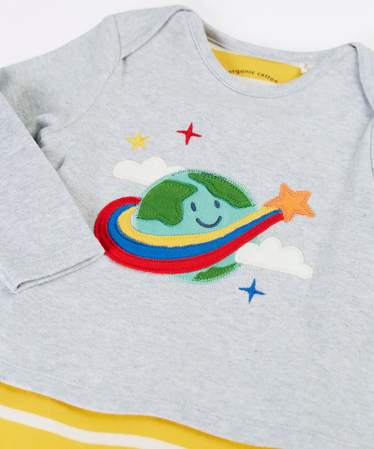 Frugi's baby all in one outfit laid flat showing close up of the cute planet earth applique on organic cotton fabric. Features a envelope neckline