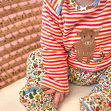 Frugi Brooke highland cow and pink stripe easy-dressing babygrow worn by baby.