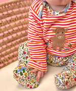Frugi Brooke highland cow and pink stripe easy-dressing babygrow worn by baby.