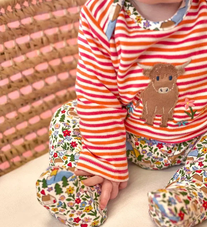 Frugi Brooke highland cow and pink stripe easy-dressing babygrow worn by baby.