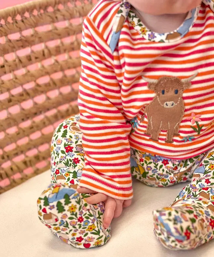 Frugi Brooke highland cow and pink stripe easy-dressing babygrow worn by baby.