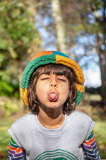 A child standing outside and wearing the Frugi kids fleece bucket hat in hotchpotch available at Babipur.