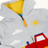 A close up of the light grey Frugi organic cotton hoodie laid flatshowing the zip and the detailing on the red tractor on the bottom
