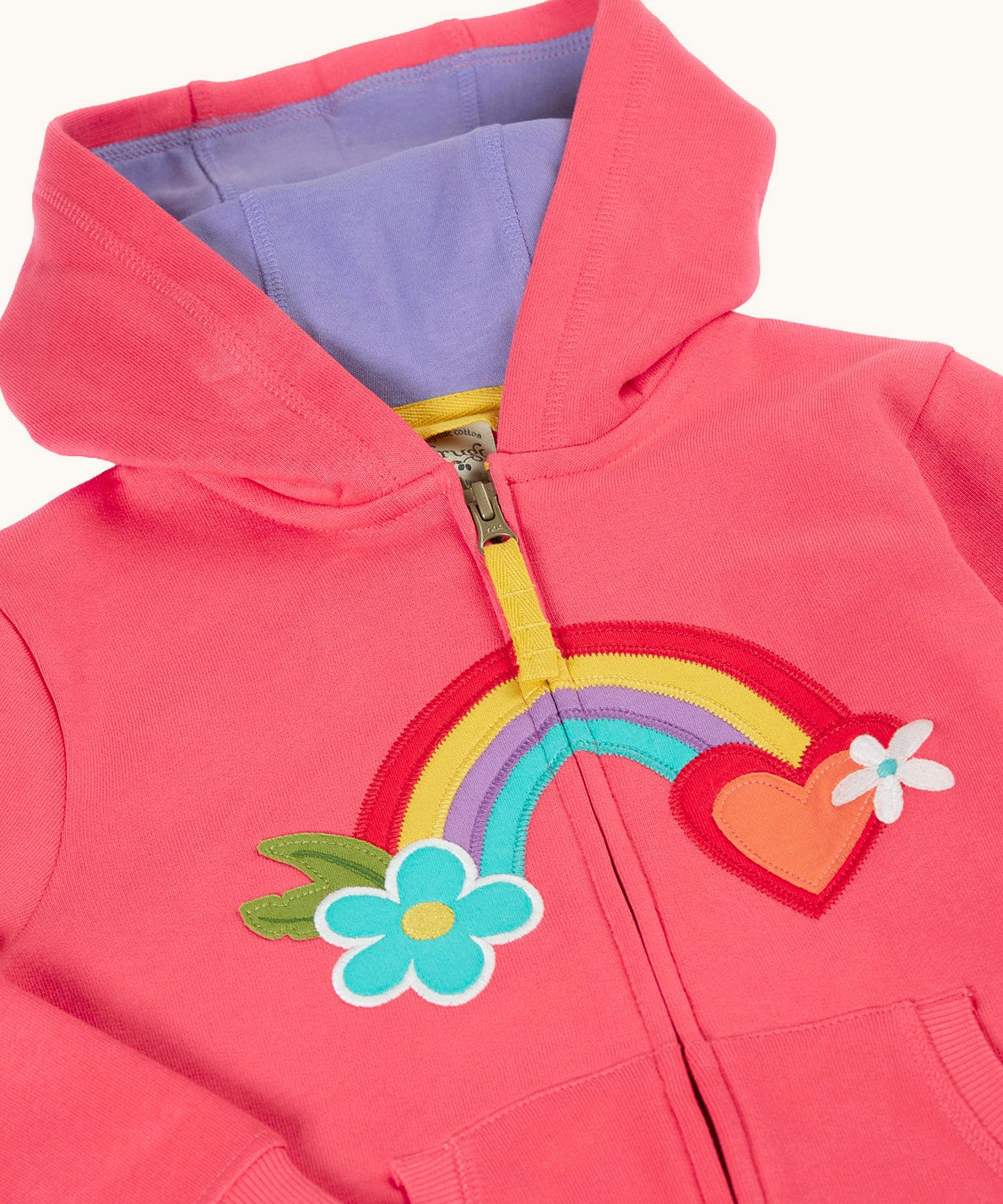 A close up of the light pink zipped hoodie with a light purple inner lining. Showing the detailing on the rainbow patch running across the middle.