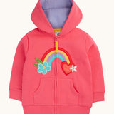Frugi organic cotton zipped  hoodie laid flat. In light pink and a purple inner lining. Has a rainbow patch in the middle with a blue flower on one end and red heart on the other. 