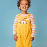 Frugi Catrin reversible dungarees in yellow cord with house applique on bib paired with a striped long sleeve top, worn by little girl.