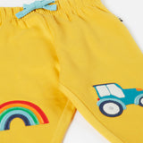 A close up of the bright yellow Frugi joggers laid flat showing the elasticated waist band with a blue tie