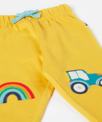 A close up of the bright yellow Frugi joggers laid flat showing the elasticated waist band with a blue tie