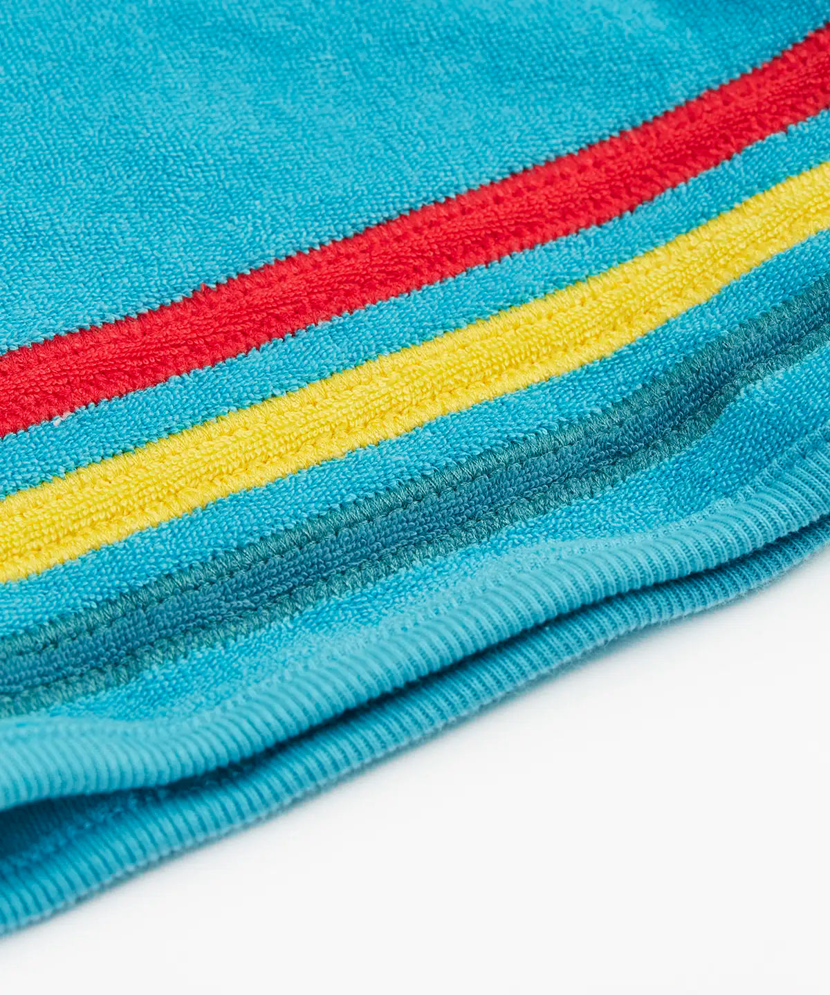 Frugi GOTS organic cotton coast towelling shorts in light blue laid flat showing the red, yellow and blue stripe detail on hem