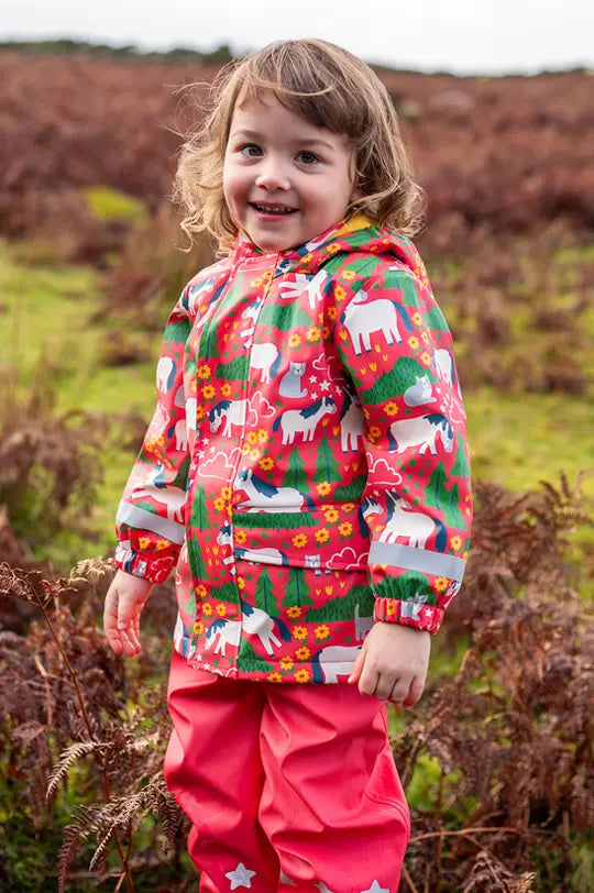 Girl wearing Frugi Puddlebuster coat in pink with horses and cats to represent Frugi outerwear at Babipur.