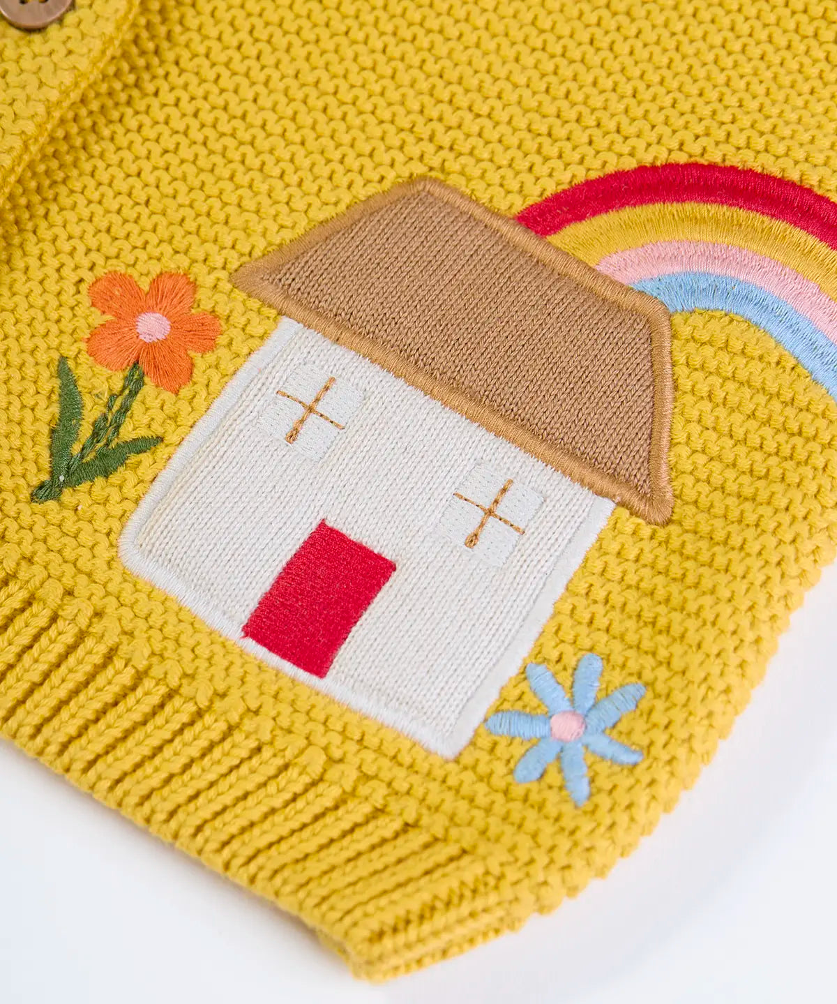 Frugi kids knitted cardigan in yellow laid flat showing a close up of the cute house applique and flower embroidery on organic cotton fabric