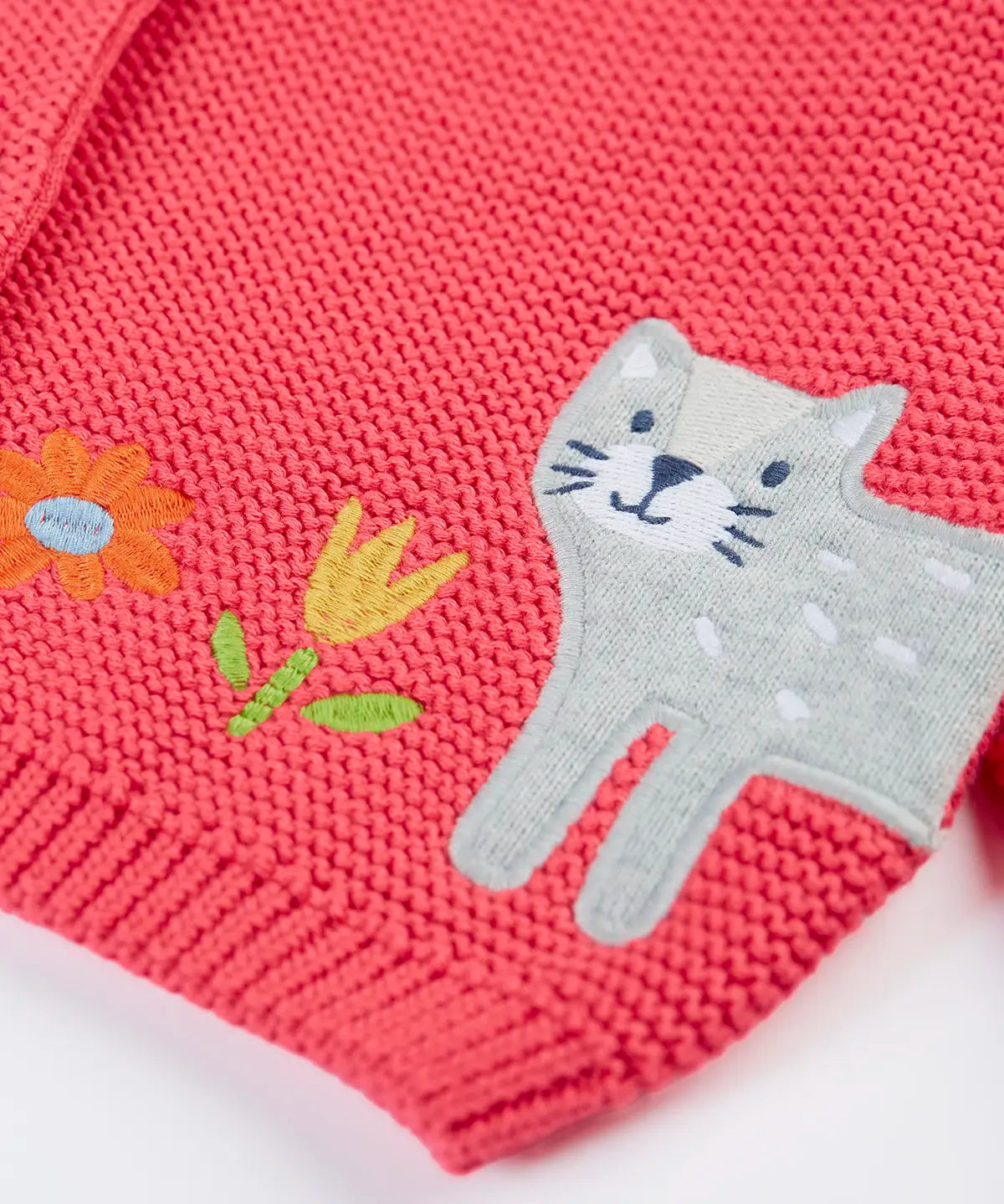 Frugi kids knitted cardigan in soft pink laid flat showing a close up of the cute cat applique on organic cotton fabric