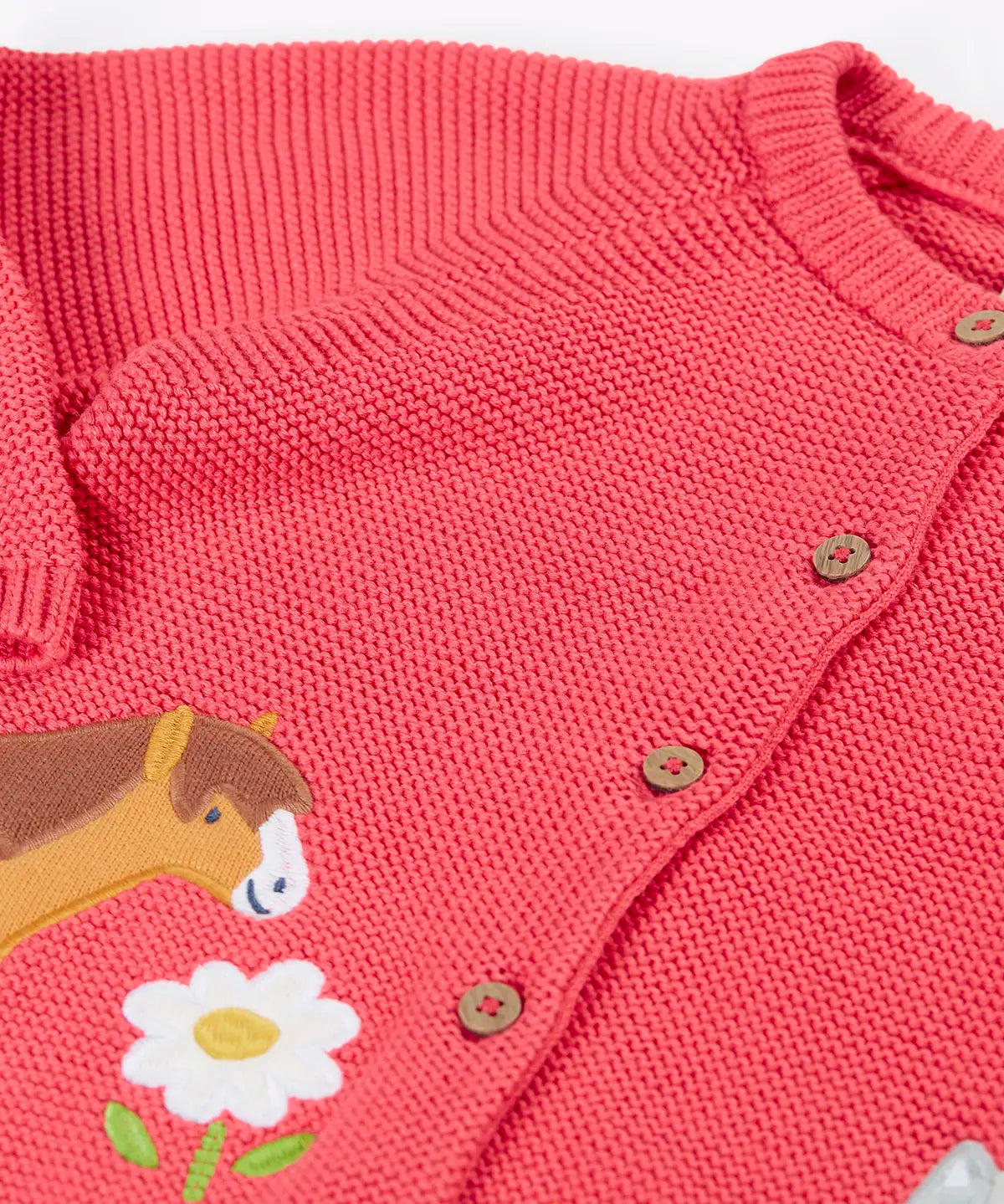 Frugi kids knitted cardigan in soft pink laid flat showing a close up of the wooden buttons fasteners on the front