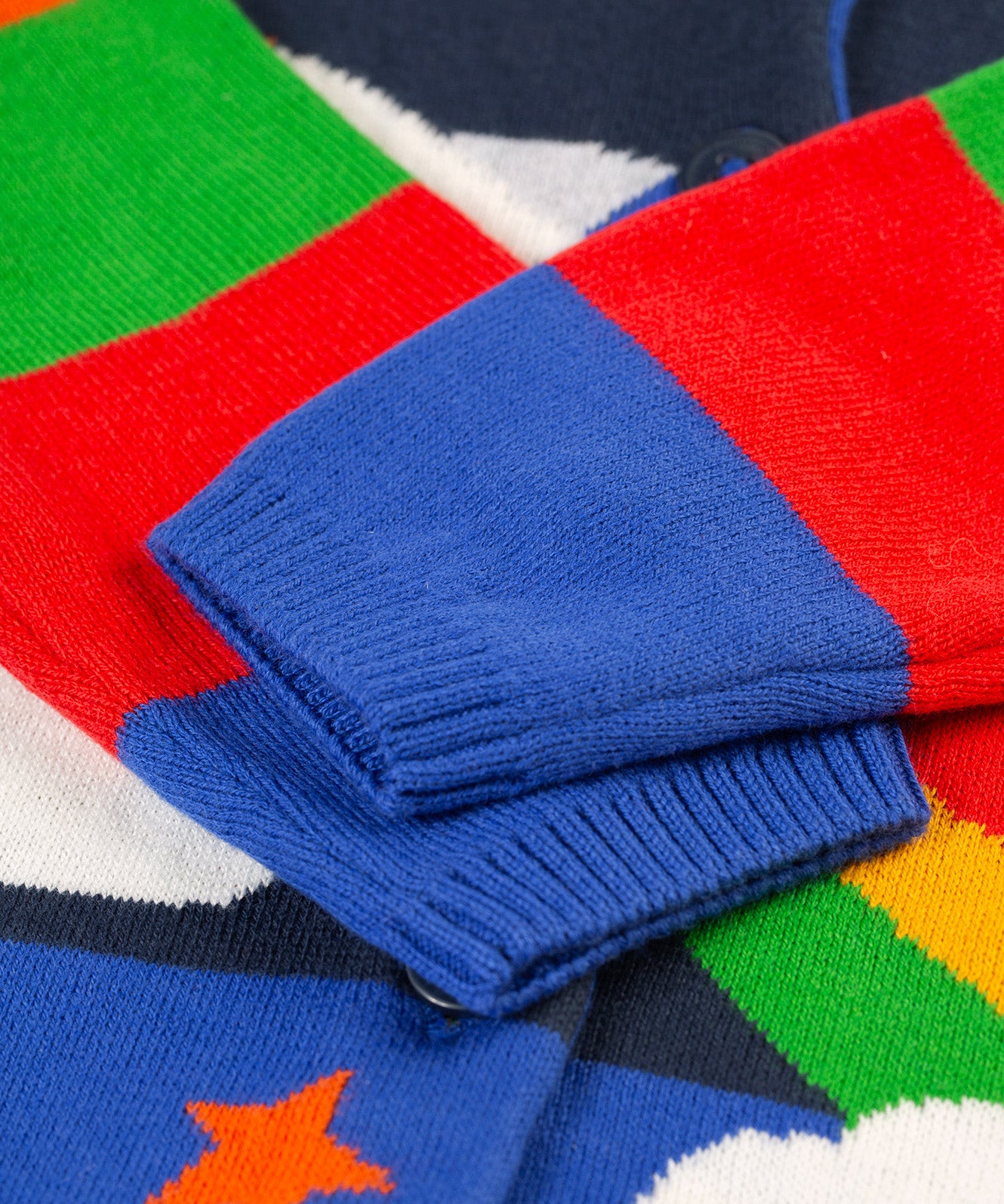 The colourblock sleeves on the Frugi Corin Knitted Cardigan - Blue Tang/Rocket Flight, in blue, red and green