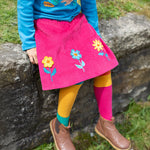 A child wearing the Frugi Norah Tights - Deep Water Colour Block with a Frugi skirt and top