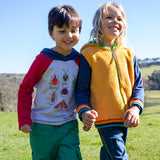 A child standing outside and wearing the Frugi compass kids hooded top in grey bug next to another child wearing the helston reversible hoodie available at Babipur.