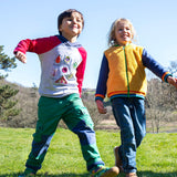 A child walking on grass and wearing the Frugi compass kids hooded top in grey bug next to another child wearing the helston reversible hoodie available at Babipur.