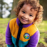 Frugi Cord Fleece Snuggle Suit in Hotchpotch colourblock with 'navigate nature' badge worn by child.