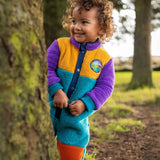Frugi Cord Fleece Snuggle Suit - Hotchpotch worn by child - a cosy blue, purple and yellow all-in-one with orange cord knee patches.