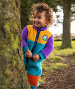 Frugi Cord Fleece Snuggle Suit - Hotchpotch worn by child - a cosy blue, purple and yellow all-in-one with orange cord knee patches.