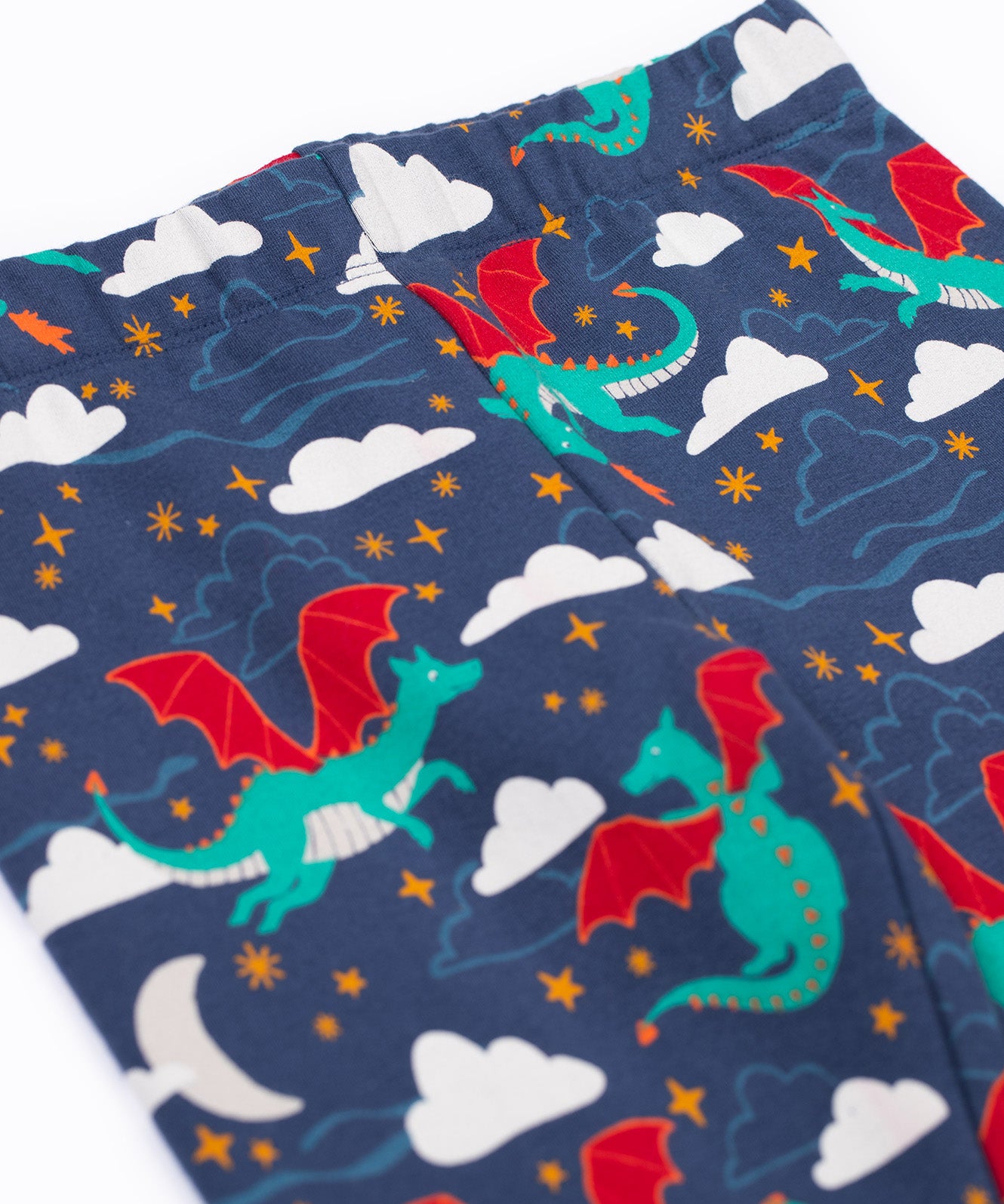 A close up of the flying green dragon print and elasticated waist band on the Frugi cosy leggings in navy/dragon skies available at Babipur.