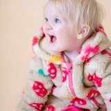 A close up of a toddler wearing the Frugi kids cosy ted snuggle suit in mushroom field available at Babipur, showing the pink zip and cuff trim detail