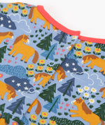 Frugi kids dress in light blue with a playful repeating shetland horse print laid flat showing popper fasteners on the back for easier dressing