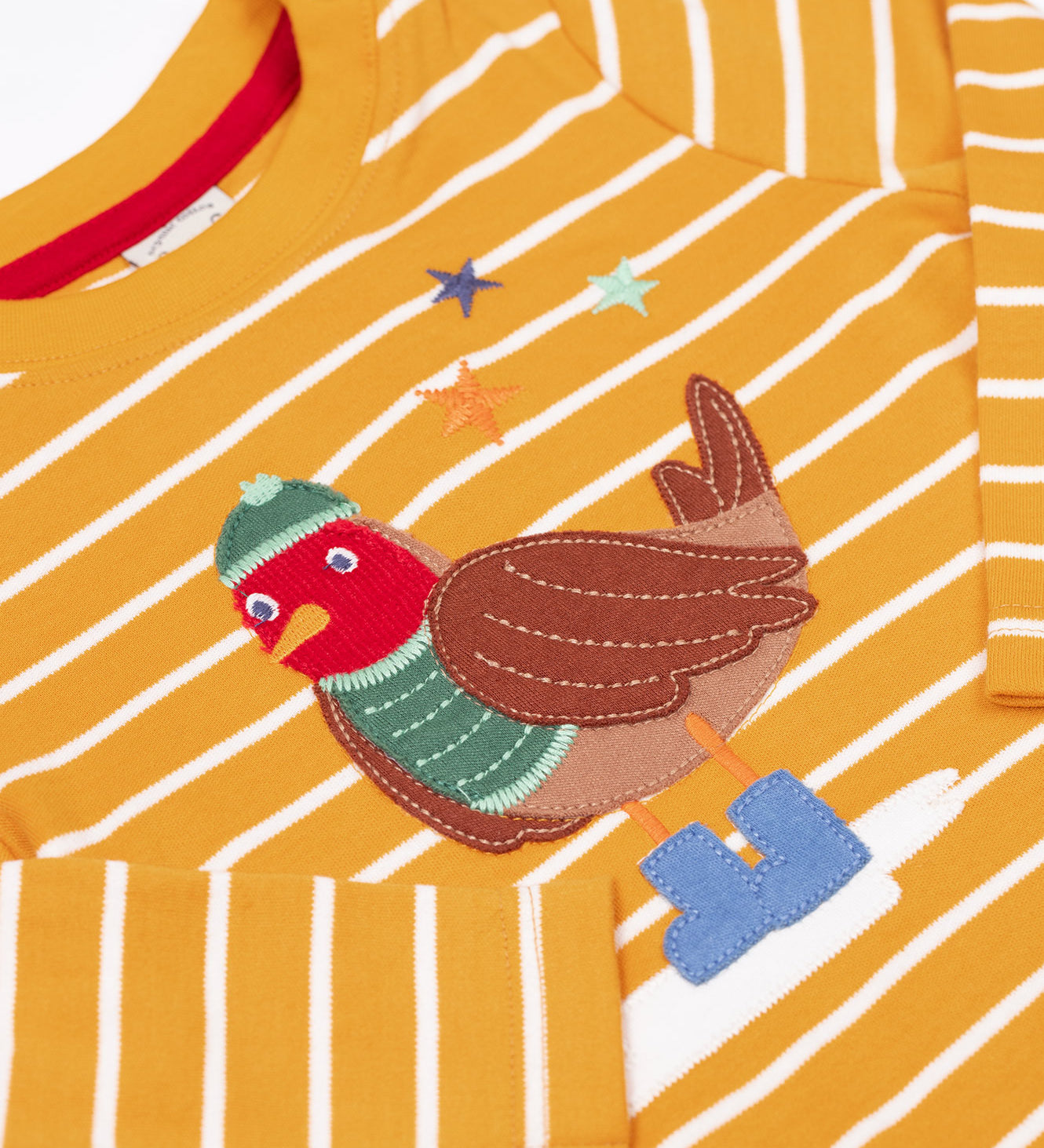 A close up of the robin applique on the Frugi discovery applique top in stripe/polar bear available at Babipur. Robin is wearing a greeb winter hat, top and blue boots.