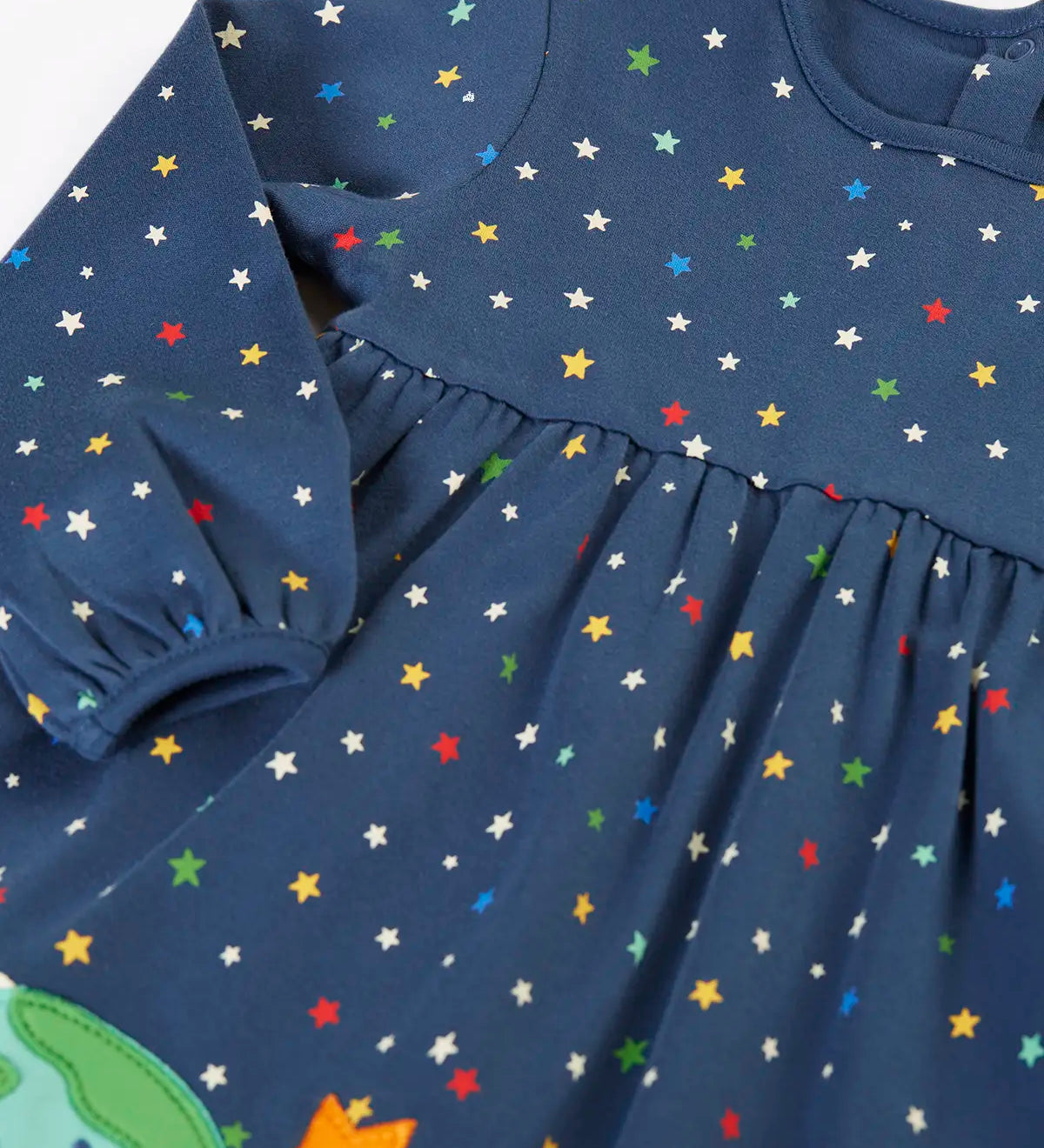 Frugi kids dress laid flat showing the repeating stars print and elasticated cuff detail on navy organic cotton fabric
