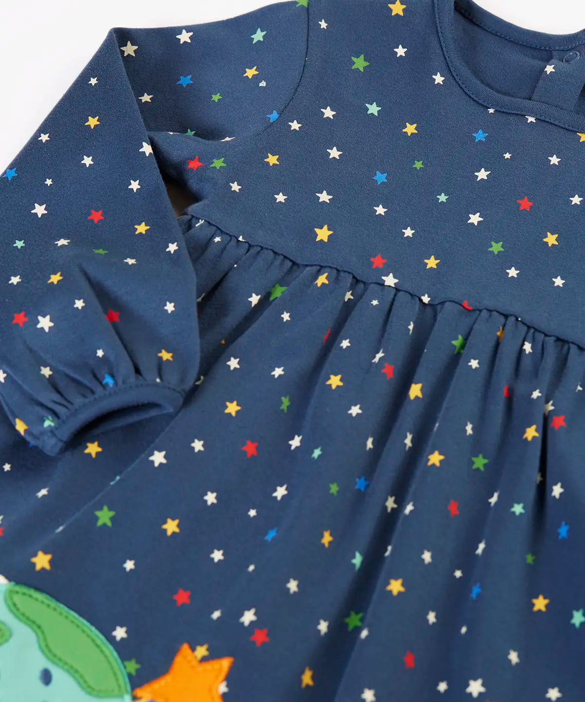 Frugi kids dress laid flat showing the repeating stars print and elasticated cuff detail on navy organic cotton fabric