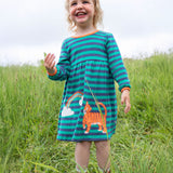 A child happily playing outside wearing the Frugi Dolcie Dress - Iguana Stripe/Tiger