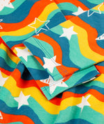 A closer look at the long sleeves, wavy rainbow stripe and white star print on the Frugi Cosy Amelia Dress - Wavy Stars
