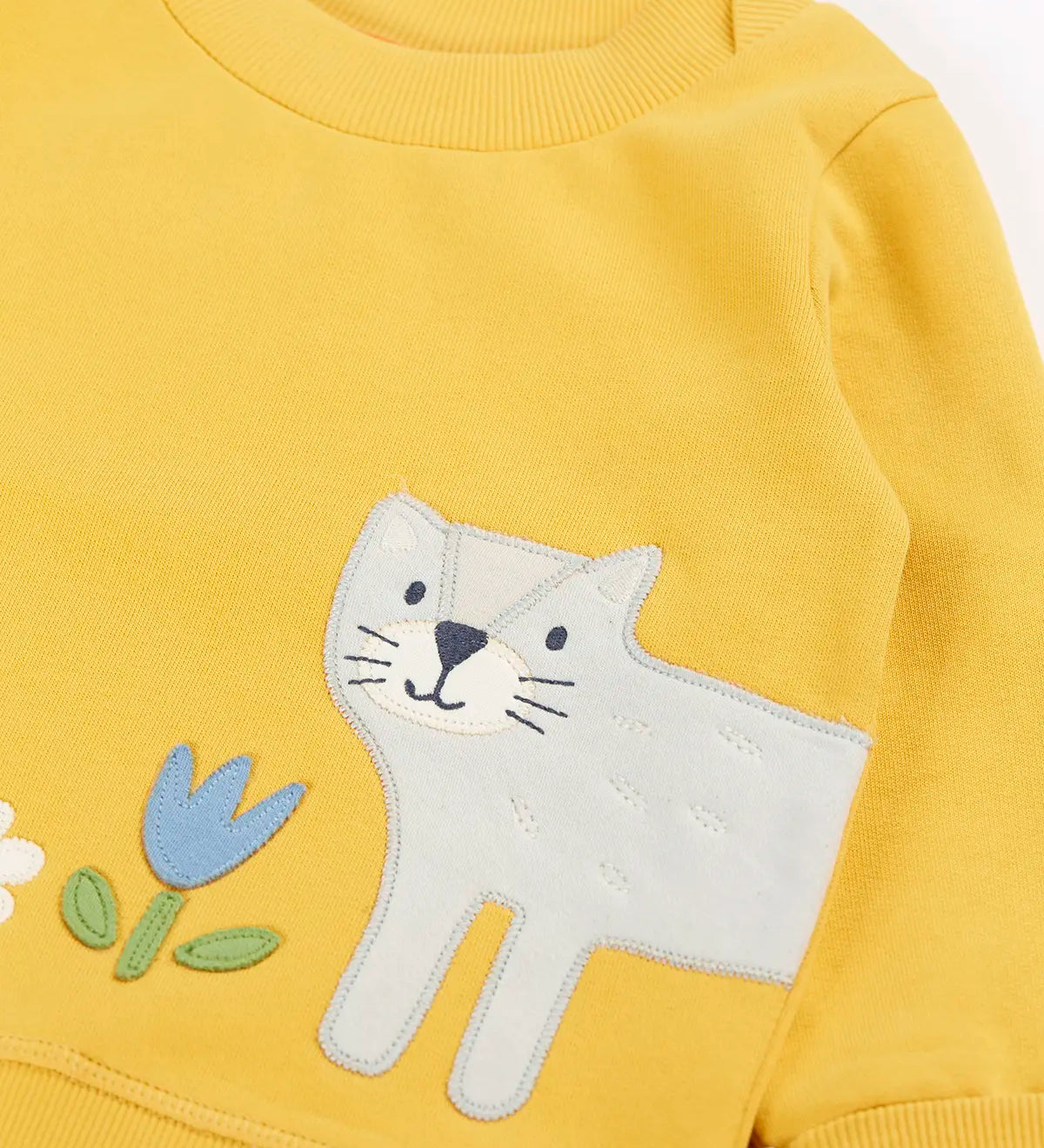Frugi kids jumper laid flat showing a close up of the cute cat and flower applique on the front on yellow organic cotton fabric