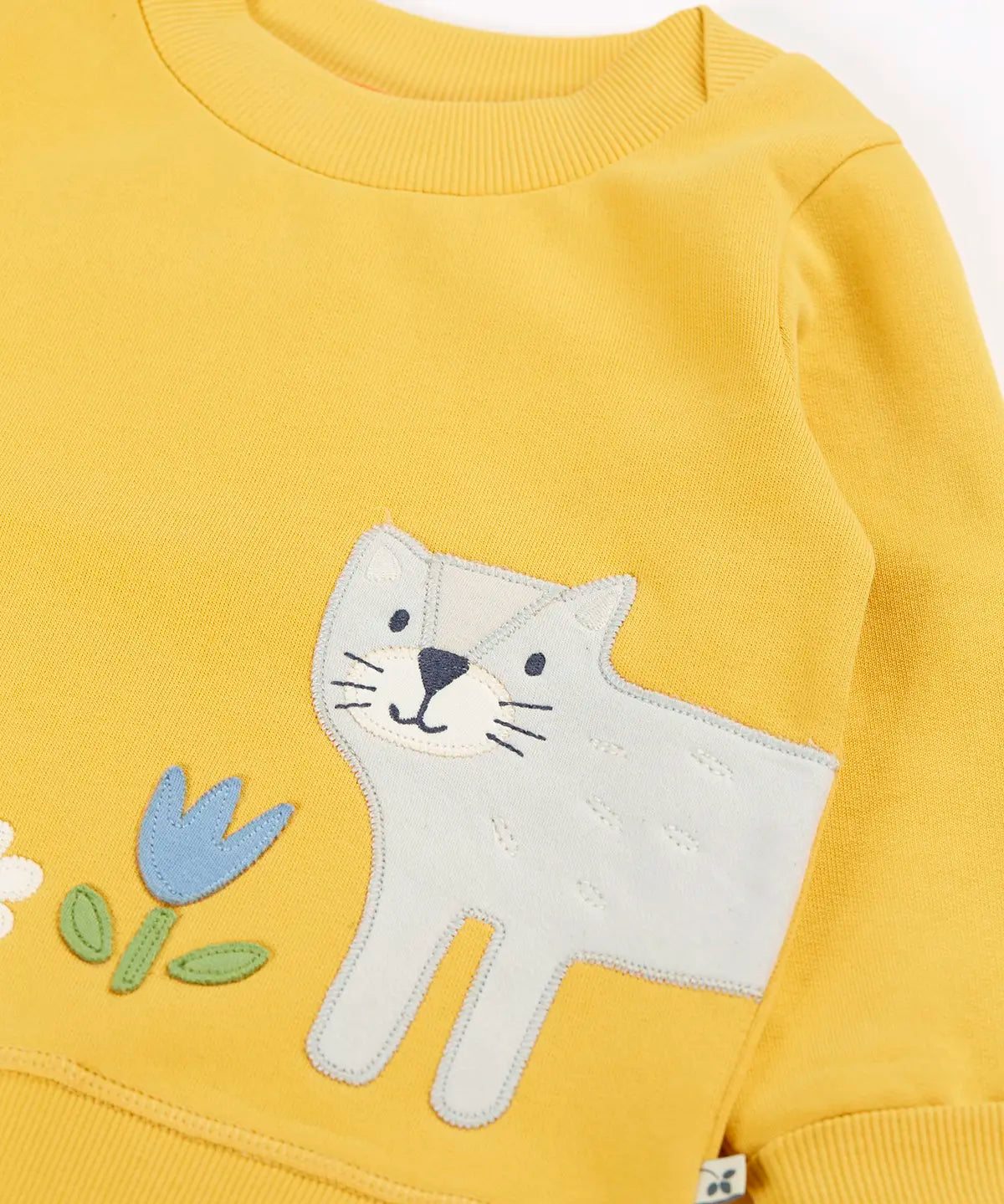 Frugi kids jumper laid flat showing a close up of the cute cat and flower applique on the front on yellow organic cotton fabric